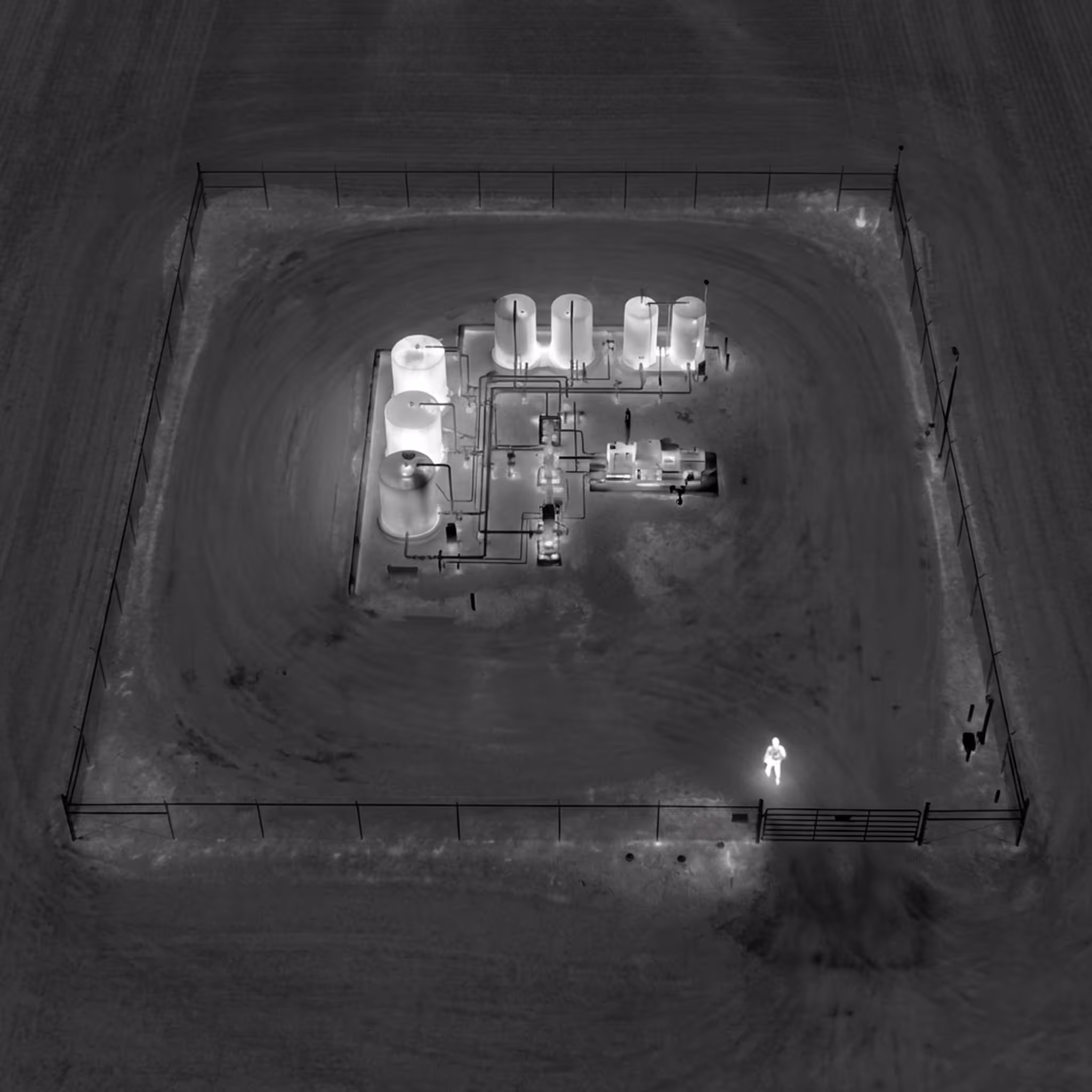 Drone de patrouille périmétrique effectuant une reconnaissance nocturne d'une plateforme de forage isolée.