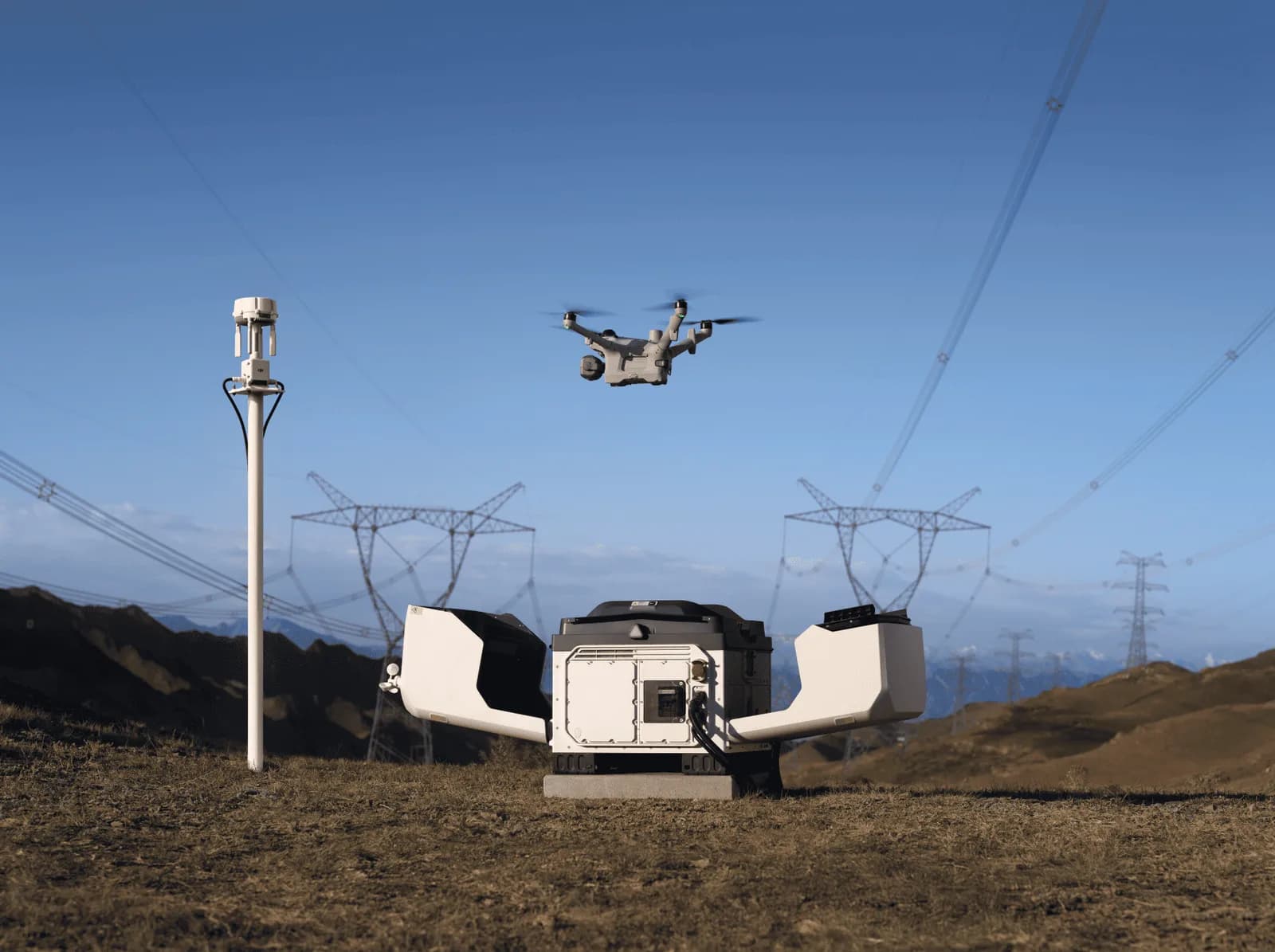 DJI Dock 4 open on a hillside under power lines as the Matrice 5TD flies above
